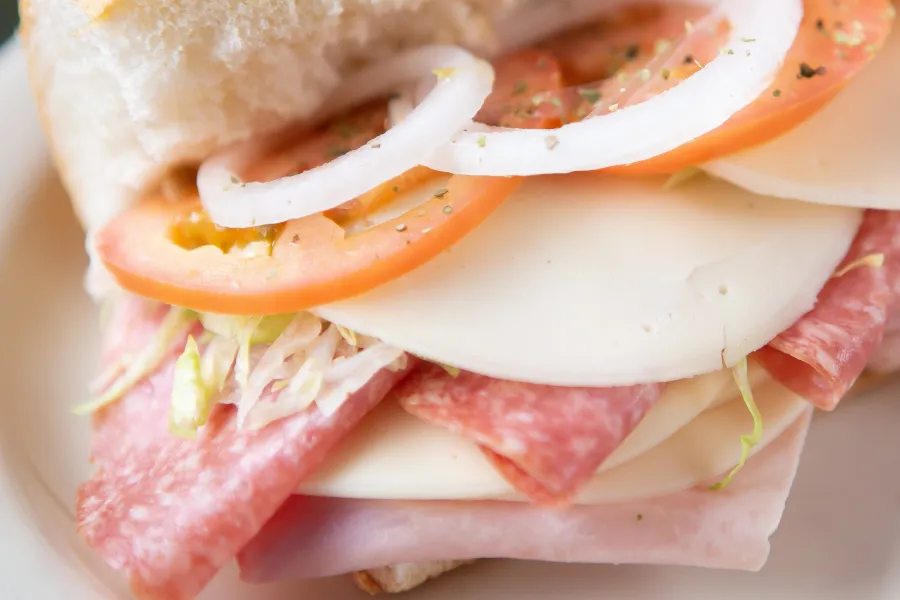 Delicious meat and cheese sticking out of an Italian sub